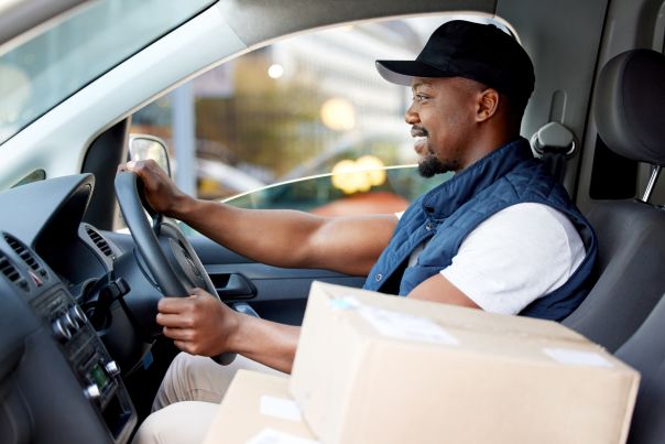 A delivery person driving a leased van with both of their hands on the steering wheel.
